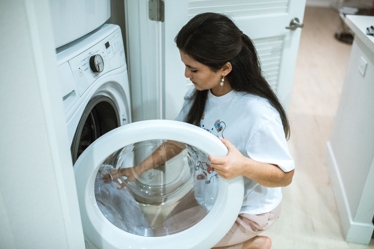 تحميل الملابس في غسالة تعبئة أمامية — loading laundry into a front-load washing machine